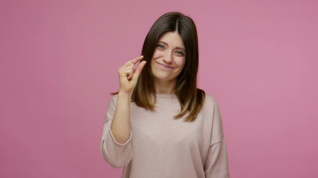 Disappointed unhappy brunette woman doing a little bit gesture with fingers, dissatisfied with small size, low rating, measuring inch, centimeter. indoor studio shot isolated on pink background