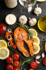 Composition with tasty grilled salmon on black background, top view