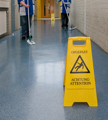 Sign wet floor. Cleaning ladies. Corridor.