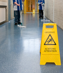 Sign wet floor. Cleaning ladies. Corridor.