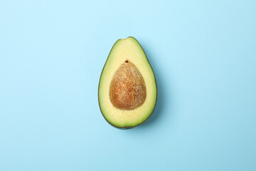 Half of fresh avocado on blue background, space for text