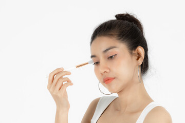 Healthy and cosmetics concept. Beauty face of young Asian woman applying make up with brush over white isolated background.
