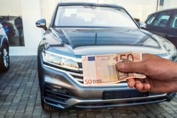 concept of buying a new car. male hand holds a euro for a successful deal