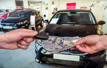 Male hand gives money and take car keys, new car as background