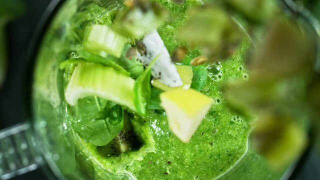 Green fresh smoothie blended in blender, top view. Healthy eating concept. Super slow motion filmed on high speed cinematic camera.
