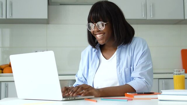 Black woman sincerely rejoicing sitting in front of laptop, lottery victory
