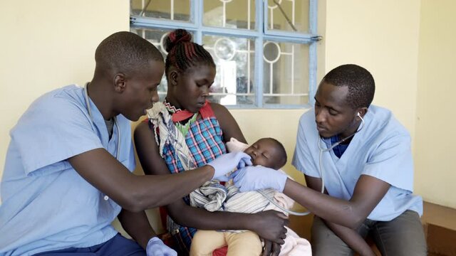 Doctors working with mothers and babies in busy neonatal clinic. Africa