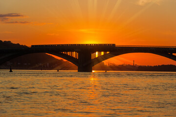 Silhouette of bridge across river at sunset in backlight