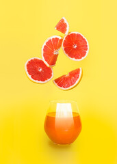 Orange juice in a glass with slices of orange on yellow background