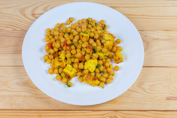 Chickpeas, stewed with Adyghe cheese on dish on rustic table