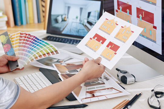 Designer looking at printed out images of house and photos of rooms when working on project