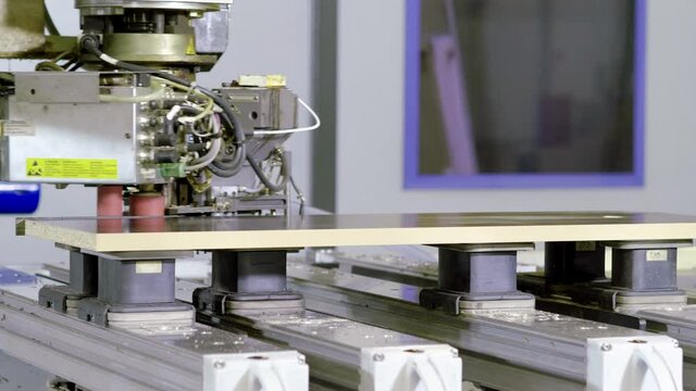 Manufacturing furniture factory with computerized automatic machinery. Close up of the production machine glues edge to furniture part. 4K