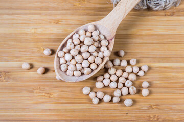 Uncooked yellow chickpeas in wooden spoon on the wooden surface