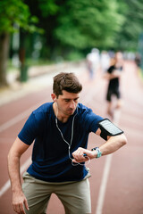 Fototapeta premium Young man checking his heart rate during work out. Young man exercising on athletics track 