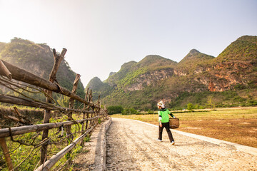 Obraz premium A femle Chinese farmer walking in the meadow of the mountains.