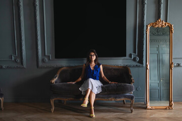 Fototapeta premium Woman in elegant clothes sitting on sofa in modern interior