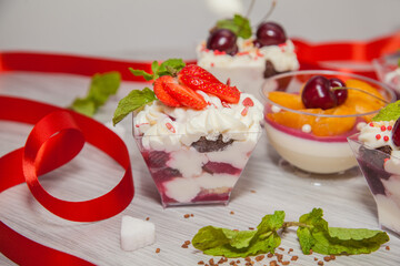Beautiful desserts with berries: cherries, strawberries, peaches, mint and whipped cream.
