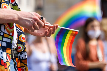 human hand hold LGBT paper flag. LGBT rainbow flag on foreground as a symbol of equality rights with blurred background. Equality rights for all people