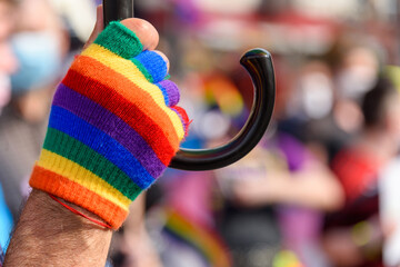human hand in rainbow color glove. LGBT rainbow flag on foreground as a symbol of equality rights...