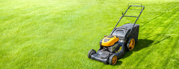 Lawn mower on fresh green lawn, freshly cut grass on summer sunny day, banner