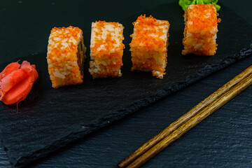Sushi roll philadelphia with salmon, rice, cheese, cucumber, avocado and caviar on a slate board. Japanese food