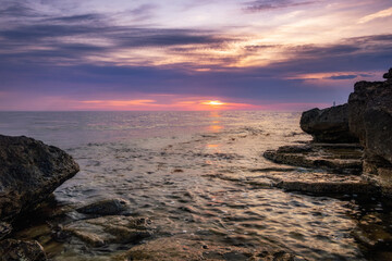 Obraz premium Dramatic sunset over beach with a natural pond in the foreground.