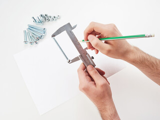 hands with a caliper measure bolts and nuts. on white background