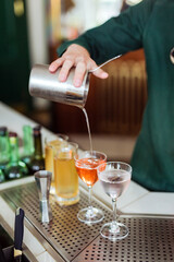 Bartender making a cocktail at the bar: pouring a drink from a shaker into a glass