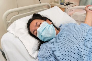Young Asian Chinese lady in Contraction pain on hospital labour room ward bed waiting to delivery...