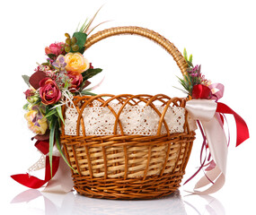 Fototapeta na wymiar Easter basket. Brown wicker basket with colorful floral decor and colored ribbons on a white background. Beautiful basket design for Easter celebration.