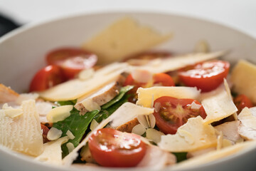 Fresh caesar salad with chicken and cherry tomatoes in white bowl