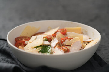 Fresh caesar salad with chicken and cherry tomatoes in white bowl