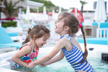 Fototapeta na wymiar Two little cute girls play in the pool.