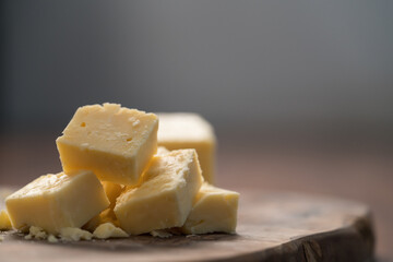 White cheddar cheese pieces on olive wood board