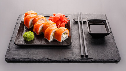 Japanese sushi on a dark stone background. Sushi set with ginger, wasabi and soy sauce. Serve with chopsticks.