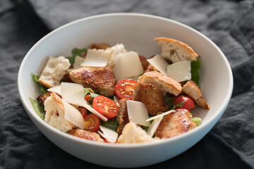 Fresh caesar salad with chicken and cherry tomatoes in white bowl