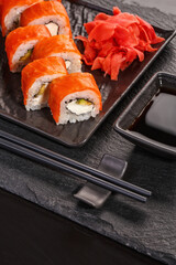 Delicious Philadelphia sushi is served in black dishes.