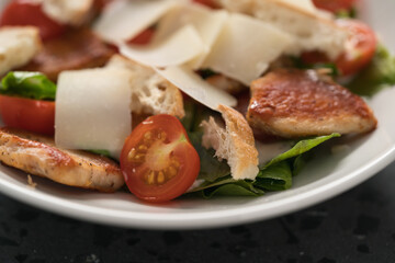 Fresh caesar salad with chicken and cherry tomatoes in white bowl