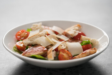 Fresh caesar salad with chicken and cherry tomatoes in white bowl
