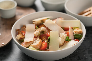 Fresh caesar salad with chicken and cherry tomatoes in white bowl