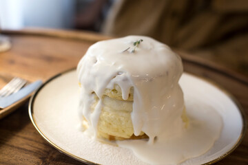 Souffle Pancakes served with syrup and fresh cream on white dish.