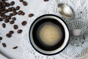 Coffee in a mug and some coffee beans in the background.