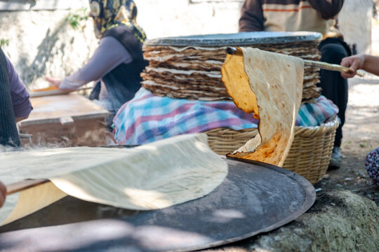 Traditional turkish  bread. Also known as "yufka ekmek" ,  natural organic homemade yufka bread. Woman cooking the handmade bread on wood fire.