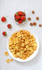 Pancake cereal in a bowl with fresh strawberries and nuts on a light background. Tasty and trendy breakfast. Organic Dutch Mini-Pancakes.