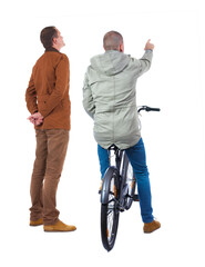 Back view of two man on a bicycle in winter jacket.