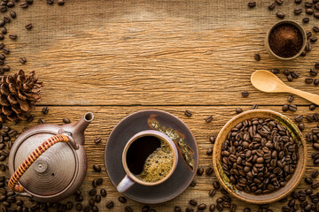 Coffee in purple cup on purple saucer Designed with coffee beans on brown plate and fine ground coffee powder with wooden spoon, kettle on wooden background.