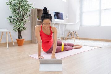 Asian woman See exercise methods from the tablet. She uses rubber resistance.