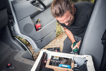 Man customizing a van - Integration of electronics underneath a front seat