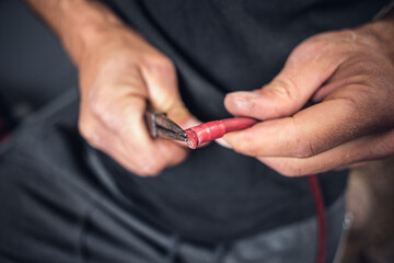 Close up of hands using pliers on cable insulation