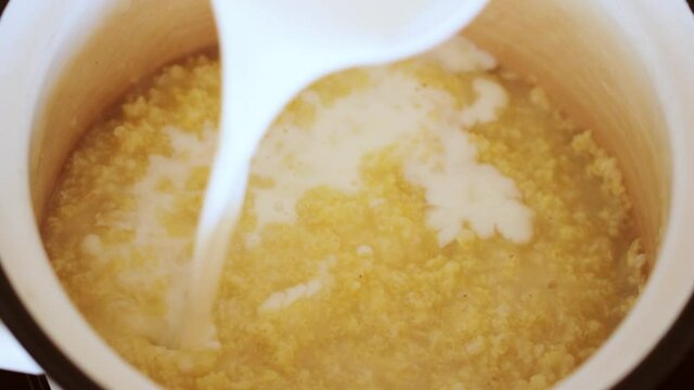 Pouring milk into boiling wheat porridge